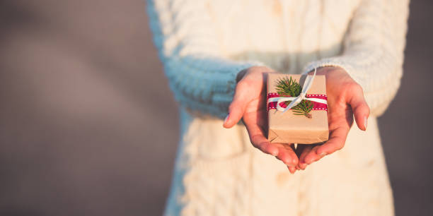 banner of a special little christmas present in woman's hands. girl holding a small xmas handmade gift. - woman holding a christmas gift imagens e fotografias de stock