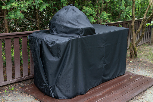 Barbecue grill Cover protecting kamado-style ceramic grill from rain. Outdoor cooking equipment.