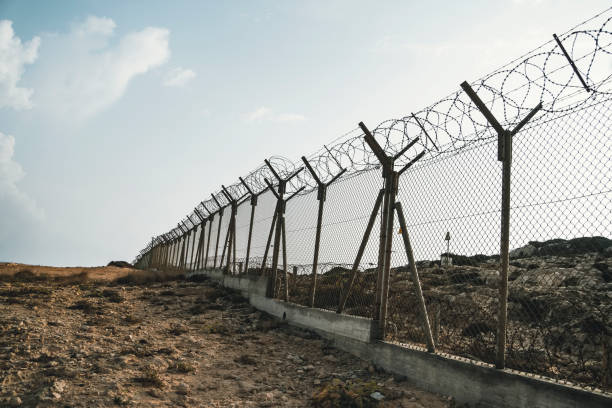 barbed wire steel wall against the immigations. Wall with barbed wire on the border of 2 countries. Private or closed military zone. barbed wire steel wall against immigations. Wall with barbed wire on the border of 2 countries. Private or closed military zone against the background blue sky. famagusta stock pictures, royalty-free photos & images