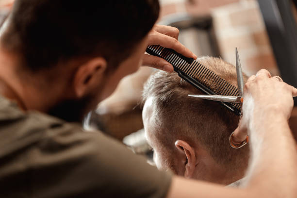 Barber and bearded man in barber shop hairdresser does haircut for bearded man in barber shop cutting hair stock pictures, royalty-free photos & images