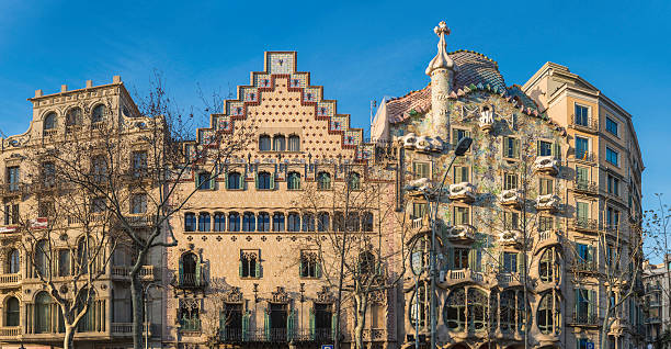 Barcelona Casa Batllo Passeig de Gracia Gaudi houses panorama Spain "The ornate facade and sinuous curves of Gaudi's iconic Casa Batllo on the Passeig de Gracia illuminated by the warm sunlight of daybreak below blue Mediterranean skies, Barcelona, Spain. ProPhoto RGB profile for maximum color fidelity and gamut." antoni gaudí stock pictures, royalty-free photos & images