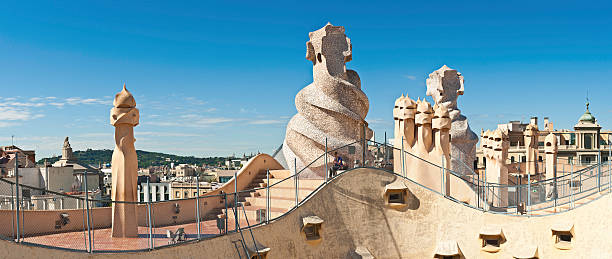 Barcelona Gaudi chimneys Casa Mila La Pedrera Spain Barcelona, Spain - June 16th, 2010: Woman sitting on the steps on the rooftop of Casa Mila, La Pedrera, beside Gaudi\'s iconic chimneys and ventilation towers under blue summer skies, Barcelona, Spain. Composite panoramic image created from six contemporaneous sequential photographs. casa milà stock pictures, royalty-free photos & images