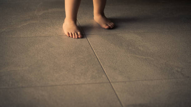 Barefoot baby are staying on heating tile floor. stock photo
