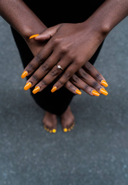 Bare-footed black ethnic woman showing her yellow-painted nails and hands on the street Bare-footed black ethnic woman showing her yellow-painted nails and hands on the street painting fingernails stock pictures, royalty-free photos & images