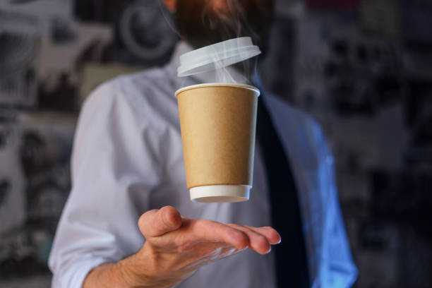 Barista and levitating paper cup of hot coffee Levitating in the air paper cup with hot coffee. Barista, a bearded young man in a white shirt with a tie, creates miracles - advertises his drink, causing it to soar. Logoplacement concept bar drink establishment photos stock pictures, royalty-free photos & images