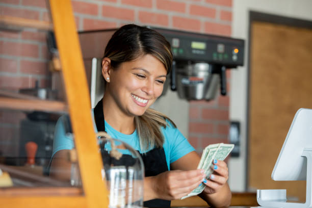 Barista counting her tips after working shift at local coffee shop stock photo
