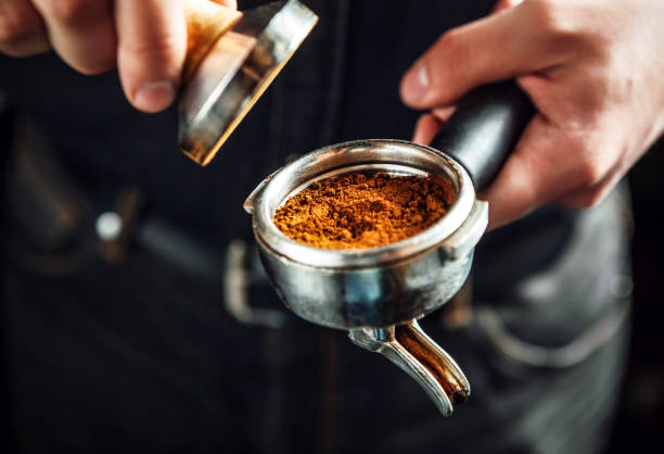 Barista holding portafilter and coffee tamper. stock photo