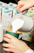 istock Barista pours frothy whipped cream into a green paper coffee cup. 1348254478