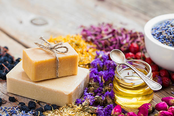 Bars of homemade soaps, honey or oil and healing herbs Bars of homemade soaps, honey or oil, heaps of healing herbs and mortar of lavender. Selective focus. homemade stock pictures, royalty-free photos & images
