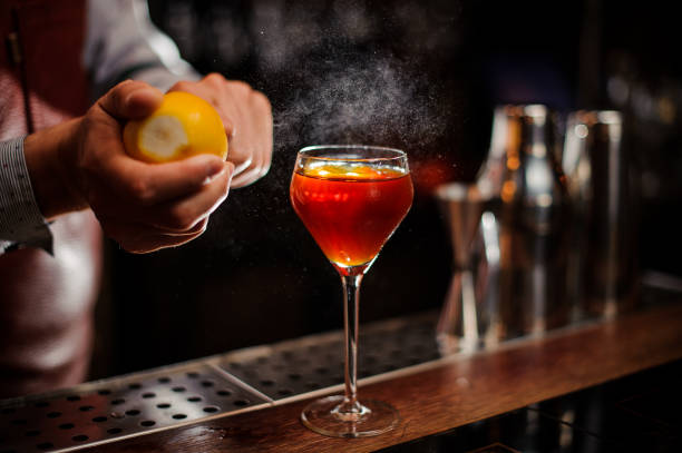 bartender đang thêm vỏ chanh vào cocktail tại quầy bar - cosmopolitan martini hình ảnh sẵn có, bức ảnh & hình ảnh trả phí bản quyền một lần