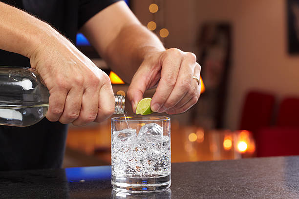 Bartender Hands squeezing lime and pouring gin or vodka into lowball glass with seltzer or tonic.  Professionally shot, color corrected, exported 16 bit depth, retouched and saved for maximum image quality.  vodka soda stock pictures, royalty-free photos & images