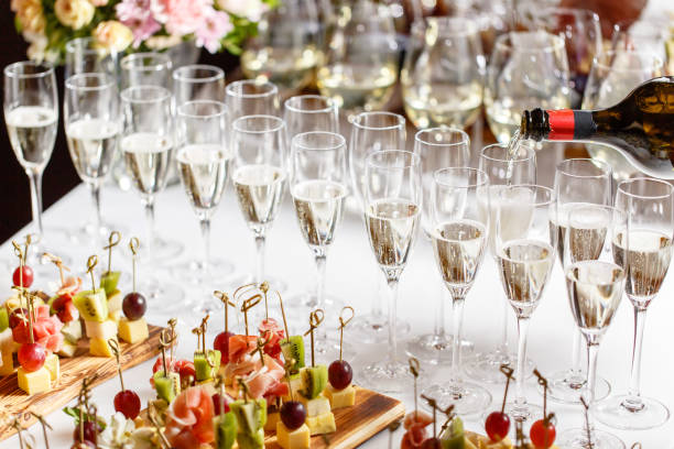 Bartender pouring champagne or wine into wine glasses on the table in restaurant. solemn wedding ceremony or happy new year banquet stock photo