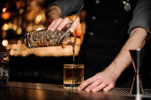 barista versa un cocktail di alcol aggiungendo whisky - bar foto e immagini stock