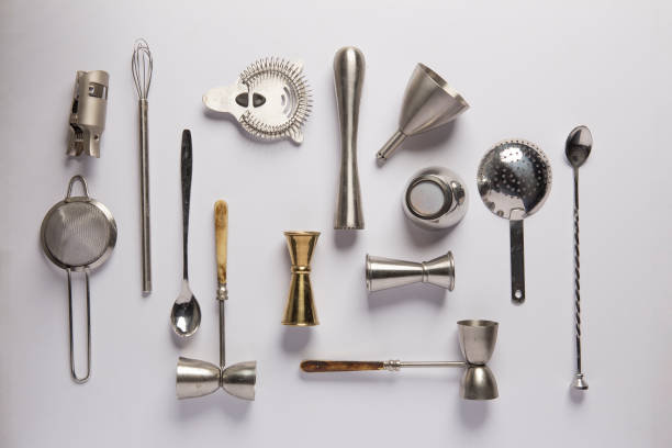 Bartender tools Flat lay composition with bartender iron tools, such as cocktail shaker, jigger, mixing glass, stirring spoon. Background is white. cocktail shaker stock pictures, royalty-free photos & images