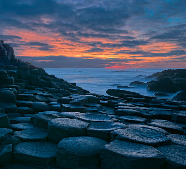 Basalt columns at dusk with majestic cloudscape at Giants Causeway in Northern Ireland Basalt columns at dusk with majestic cloudscape at Giants Causeway in Northern Ireland. basalt column stock pictures, royalty-free photos & images