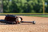 istock Baseball in a mitt with a black bat low angle selective focus view on a baseball field 1334171721