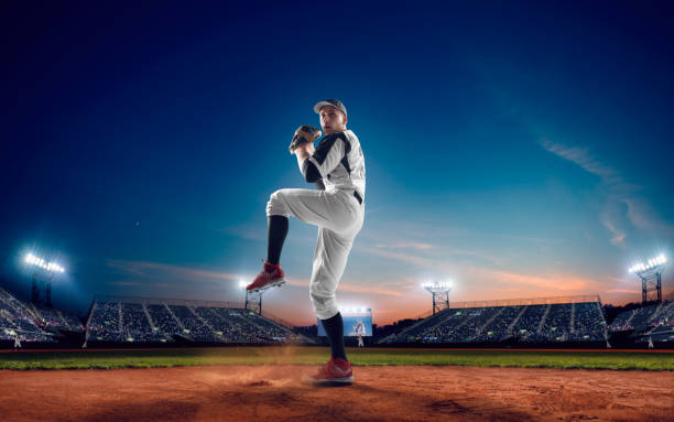 Baseball Baseball player at professional baseball stadium in evening during a game. baseball player stock pictures, royalty-free photos & images