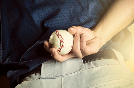 A close up view of the baseball pitchers hand just before throwing a fastball in a game. Focus on the fingers and the ball