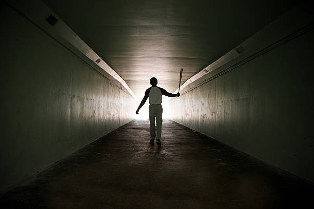 Baseball player walking out of stadium tunnel swinging bat  In a  tunnel with a grungy look for effect baseball sport stock pictures, royalty-free photos & images