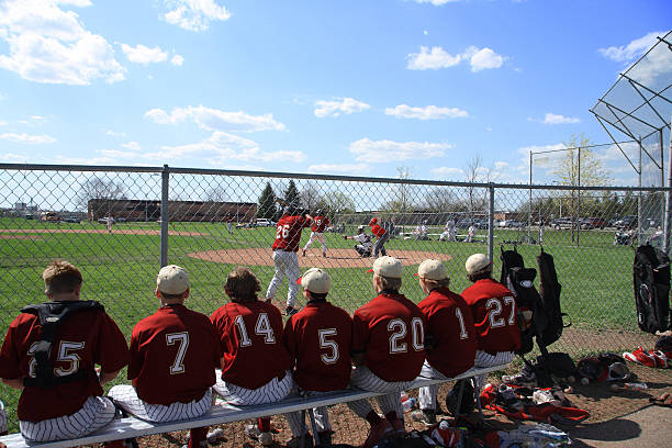 Baseball players on bench watching game through chain stock photo