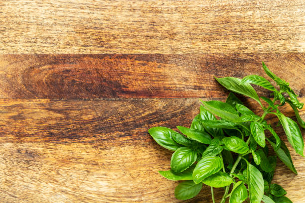 Basil twig on a vintage wood chopping board. Flat lay, top view with copy space. stock photo