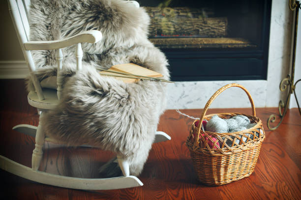 Basket with balls of yarn near chair and fireplace stock photo
