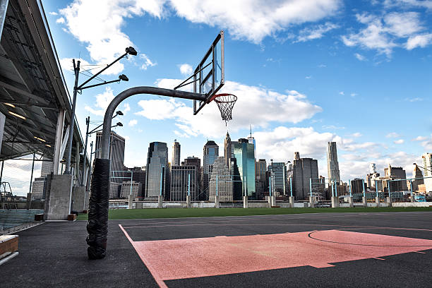 Basketball courtyard in the city New York skyscrapers are viewed behind the empty basketball courtyard. courtyard stock pictures, royalty-free photos & images