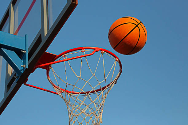 A basketball in a net on a blue sky background. The ball hit the ring. sport. stock photo