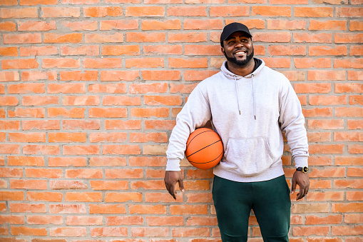 Young man holding a basketball ball. About 30 years old, African male.