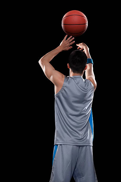 basketball player throwing ball, black background - basketball player back stockfoto's en -beelden