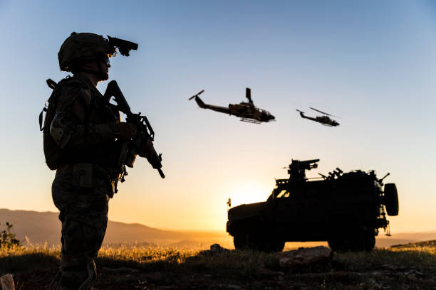 Battlefield with a soldier, armored vehicle and flying helicopters at sunset stock photo