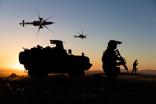 日落時分，戰場上有士兵、裝甲車和飛行直升機 - 防地雷反伏擊車 個照片及圖片檔
