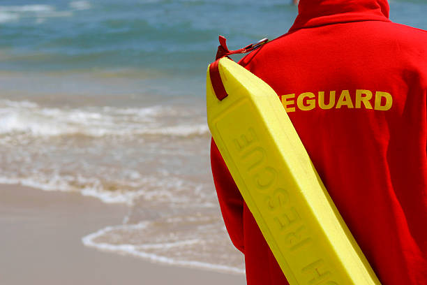 Baywatch Lifeguard With Float At A Beach A lifeguard complete with rescue float monitors their beach lifeguard stock pictures, royalty-free photos & images