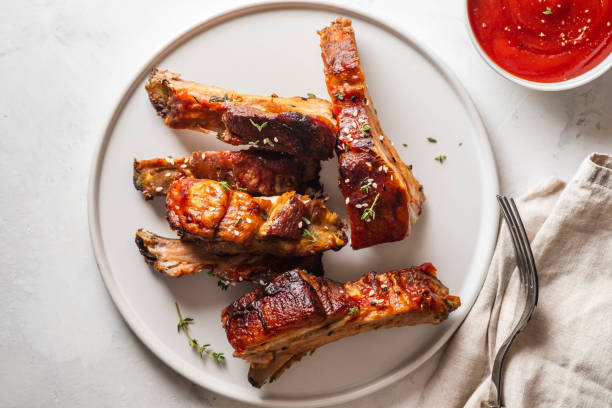 Bbq pork ribs with chili sauce on white plate. Pork ribs on slate background. Copy space. stock photo
