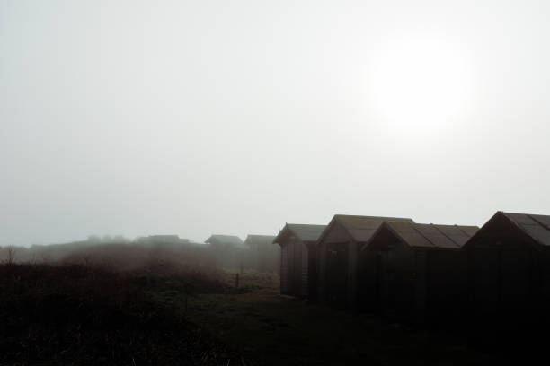 beach huts in the mist stock photo