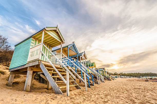 beach huts Long line of colorful beach huts at sunset. beach hut stock pictures, royalty-free photos & images