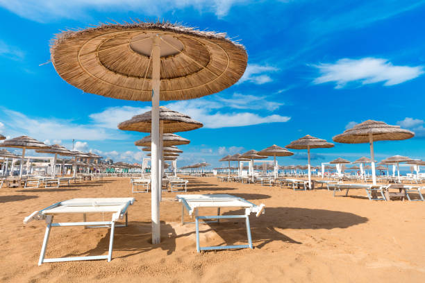 Beach in Rimini Beach in Rimini. Italy. Sun umbrellas on blue sky background on seashore. Summer background. emilia romagna stock pictures, royalty-free photos & images