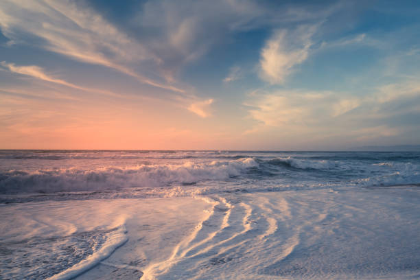 Beach sunset. Empty sand beach, sea waves, and sun setting down the horizon. blue and pink colors, copy space stock photo