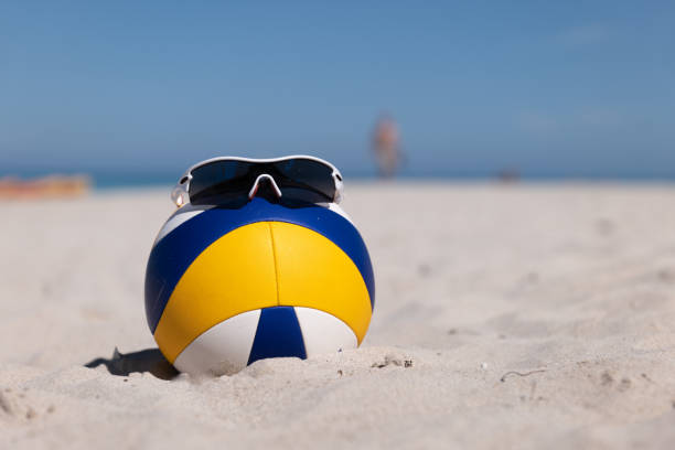 Beach Volleyball. Game ball with glasses on top under sunlight blue sky on sand stock photo