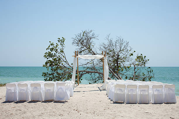beach wedding chuppa canopy arbor and chairs facing ocean Empty chairs facing the ocean on a beach in Florida, prepared for a wedding. A simple arbor (also called a chuppa or canopy) is set up in the center. chupah stock pictures, royalty-free photos & images