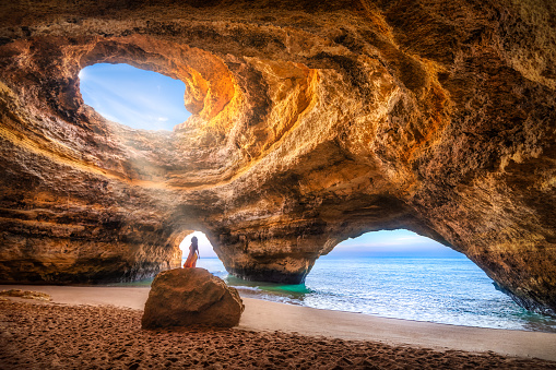 Woman alone under the sunlight in the natural Sea Cave of Benagil, Algarve, Portugal