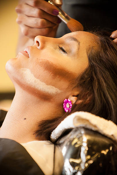 Beautician applies make up to a pretty, beautiful Latino Customer. stock photo