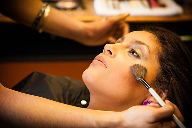 Beautician applies make up to a pretty, beautiful Latino Customer. stock photo