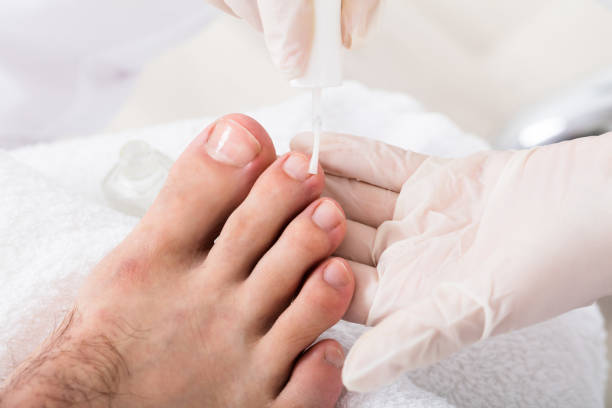 Beautician Applying Nail Oil Beautician Applying Moisturizing Nail Oil To Person's Feet man pedicure stock pictures, royalty-free photos & images