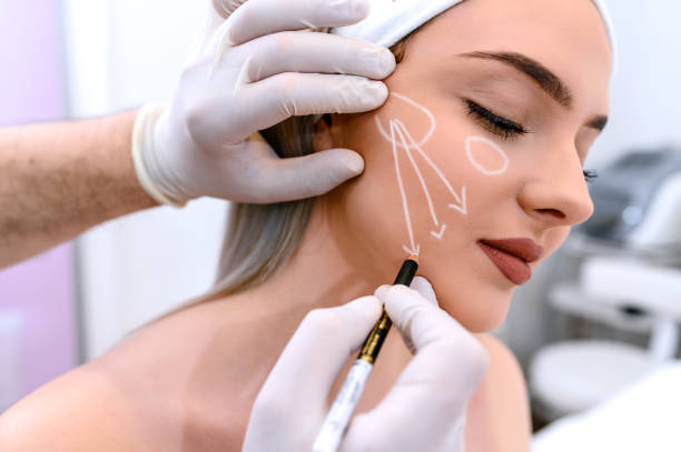 Beautician draw correction lines on woman face stock photo