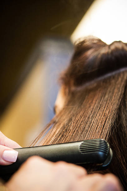 Beautician, Hair Dresser uses Hair Straightener on Customer's Hair stock photo