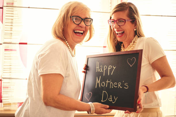 Beautiful adult daughter and her senior mom enjoying together at home. Happy Mother's day. stock photo