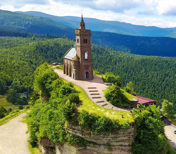 Beautiful  aerial view of St. Leon chapel at hilltop  Rocher de Dabo or Rock of Dabo, red sandstone rock butte. Moselle-Vosges mountains. Lorraine, France. Tourism and vacation concept Beautiful summer aerial view of St. Leon chapel dedicated to Pope Leo IX atop of Rocher de Dabo or Rock of Dabo, red sandstone rock butte, and Moselle-Vosges mountains and valleys. Lorraine, France vosges department france stock pictures, royalty-free photos & images