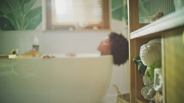 Beautiful African ethnicity woman relaxing in modern bathroom. Meditating in hot water stock photo