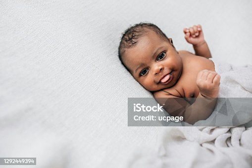 istock Beautiful African-American newborn little boy just a few weeks old swaddled in a cream colored soft blanket with copy space 1292449394